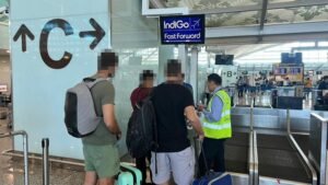 Three Serbian nationals stand at the departure gate at Ngurah Rai International Airport in Bali, escorted by an immigration officer following their deportation for operating a fishing tour business without proper work permits. The individuals, detained by Indonesian authorities, are seen awaiting their flight under IndiGo's 'Fast Forward' service, highlighting Indonesia's stringent enforcement of visa regulations for foreign nationals to protect local businesses.